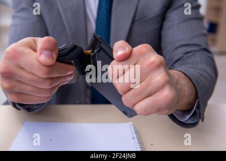 Giovane impiegato di sesso maschile insoddisfatto del lavoro eccessivo in ufficio Foto Stock