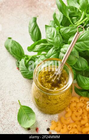 Vasetto con salsa di pesto fatta in casa su fondo rustico con parmigiano, olio d'oliva, pesto di sause, basilico e aglio. Copia sfondo spazio. Foto Stock