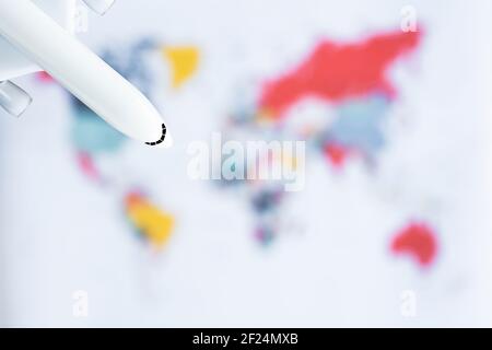 (Messa a fuoco selettiva) aereo modello bianco isolato su una mappa del mondo sfocata. Concetto di viaggio, disposizione piatta con spazio di copia. Foto Stock