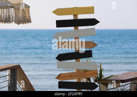 Cartelli in legno sulla spiaggia. Indicazione di direzione sullo sfondo del mare. Foto Stock
