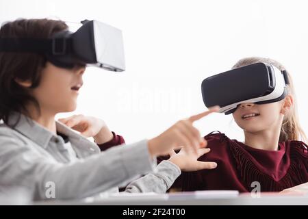 studentessa nel visore vr tocca il compagno di classe puntando con il dito primo piano sfocato Foto Stock