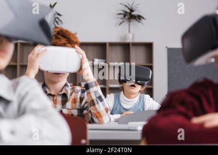 incredibile gioco per scolaresche con visore vr vicino ai compagni di classe su offuscato primo piano Foto Stock