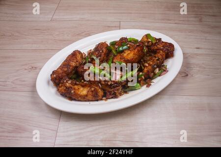 Il paneer Chilis è un piatto indiano, con cubetti di paneer e pomodori, cipolle, cipolle primaverili, salsa di peperoncino. Servito su rustico fondo di legno, fuoco selettivo Foto Stock