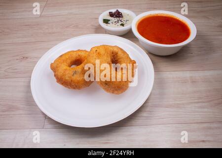 Vada / Medu Vadai con Sambar - popolare spuntino dell'India del Sud servito su lamiera d'acciaio, fuoco selettivo Foto Stock