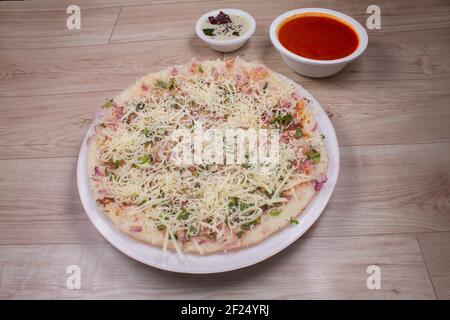 Uthappam o Uttapam è un tipo di salsa dell'India meridionale più spessa, con pomodoro, cipolla, peperoncino e formaggio Foto Stock