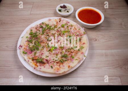 Uthappam o Uttapam è un tipo di salsa dell'India meridionale più spessa, con pacchetti di pomodoro, cipolla, peperoncino. Foto Stock