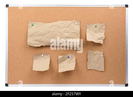 Pannello in sughero con telaio in alluminio e pezzi di carta marrone attaccati Foto Stock