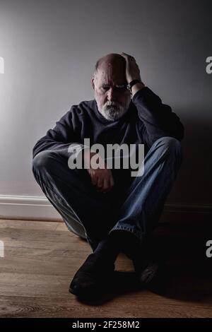 Vecchio depresso seduto sul pavimento. Foto Stock