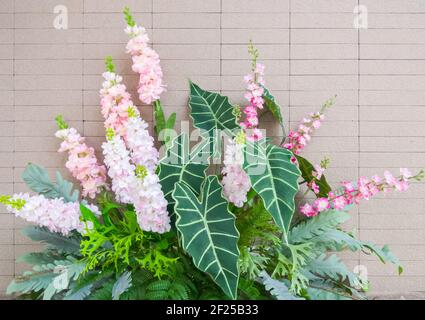 Fiori artificiali dal tessuto e l'albero di plastica vicino all'ingresso della sala riunioni per la decorazione nell'edificio degli uffici. Vista frontale con il c Foto Stock