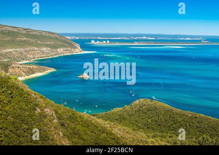 Bellissimo paesaggio del Parco Naturale Arrábida in Portogallo, con le montagne, le spiagge, il mare blu e sullo sfondo la penisola di Troia. Foto Stock