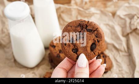 Mani femminili che tengono i biscotti del chip del cioccolato. Messa a fuoco selettiva Foto Stock