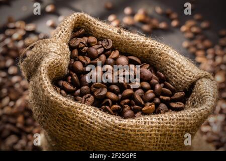 Schizzi di caffè in grani in borsa sul tavolo di legno. La luce del mattino Foto Stock