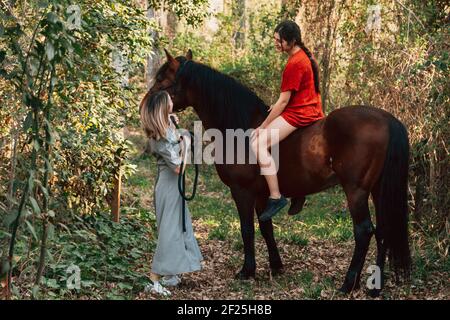 Due amici donne che chiacchierano e fanno un giro con loro cavallo attraverso la campagna Foto Stock
