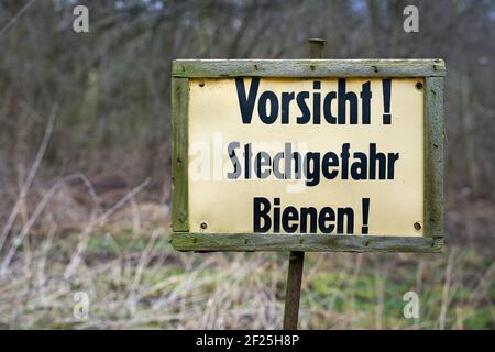 Segno al bordo della foresta con l'iscrizione Attenzione pericolo di puntura delle api Foto Stock