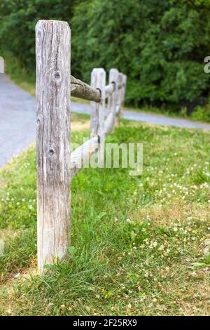 Vecchio recinto di legno vicino alla strada nel parco. Foto Stock