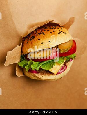 Un succoso cheeseburger si rompe nello sfondo artigianale. Carta Kraft. Foto promozionale. Foto di alta qualità Foto Stock