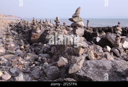 Spiaggia costa con centinaia di pietre equilibranti o rocce bilanciate impilate / impilate come cairns dal pubblico a Barton on sul mare durante la crisi Covid. Foto Stock