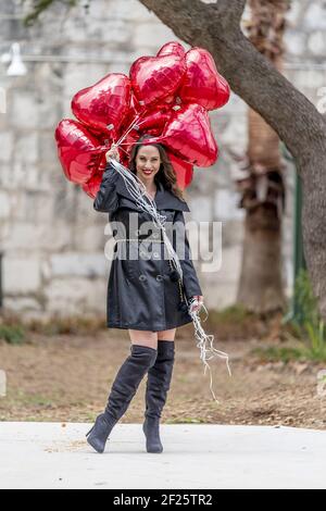 La splendida Brunette ispanica celebra il giorno di San Valentino con una dozzina Palloncini con cuore rosso Foto Stock