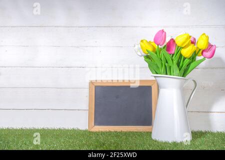 Biglietto d'auguri per il giorno della mamma. Tulipani bouquet in vaso e cartellino di saluto su legno bianco e legno plank sfondo spazio copia Foto Stock