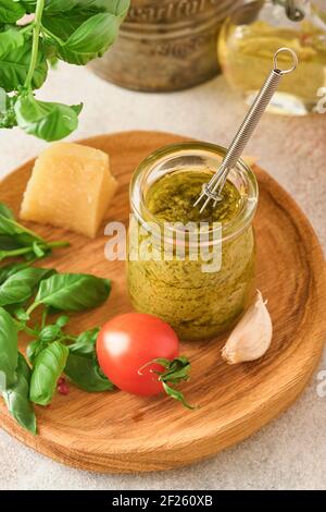 Vasetto con salsa di pesto fatta in casa su fondo rustico con parmigiano, olio d'oliva, pesto di sause, basilico e aglio. Copia sfondo spazio. Foto Stock