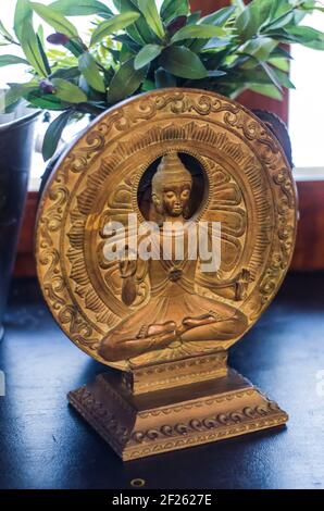 Statuina di Buddha su sfondo di cerchi di bronzo. Figurina sacrale all'interno. Foto Stock
