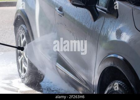Autolavaggio su autolavaggio senza contatto. Un uomo lava l'auto. Mettere la vettura in ordine Foto Stock
