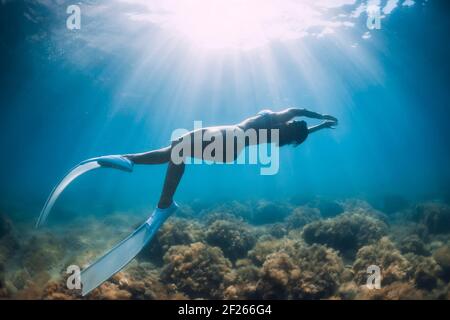 Il freediver scivola su un mare sabbioso con pinne bianche. Donna libera subacquea in mare trasparente Foto Stock