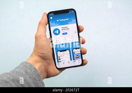 Kharkov, Ucraina - 9 marzo 2021: Applicazione telegramma in app store, popolare messaggero per chattare con gli amici, l'uomo tiene smartphone Foto Stock
