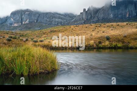 Andringitra Massiccio visto dal campo base durante il trekking a Pic Boby (la vetta più alta accessibile del Madagascar), piccolo fiume che scorre in primo piano Foto Stock