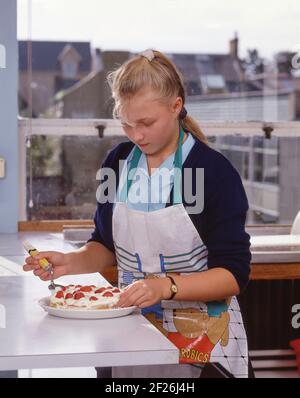 Giovane studentessa che si cottola in cucina e catering, Guildford, Surrey, Inghilterra, Regno Unito Foto Stock