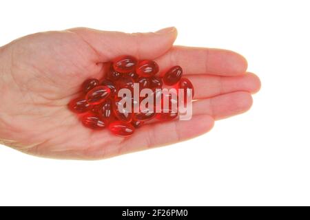 Capsule di olio di krill. Capsule di gelatina rossa con olio di krill in mano isolato su fondo bianco.Fonte di acidi grassi omega. Integratori. Dietetica Foto Stock