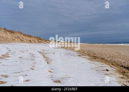 La spiaggia di Montauk durante l'inverno, con neve che copre parte della sabbia Foto Stock