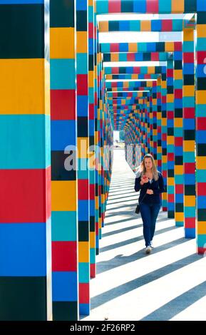 Donna che guarda lo smartphone mentre cammina attraverso l'arco colorato, Città del Messico, Messico Foto Stock