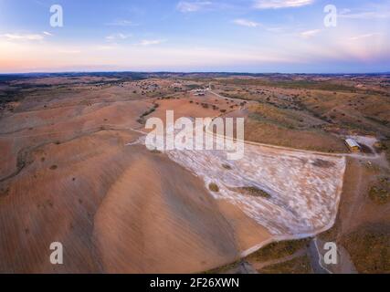 Drone panorama aereo di un deserto come paesaggio collinare con pietre di marmo polvere al tramonto a Terena, Portogallo Foto Stock