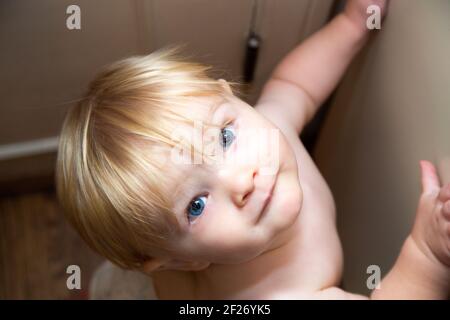 Carino bambino in un pannolino guardando in su la macchina fotografica Foto Stock