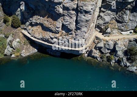 Ciclisti sul ponte a sbalzo sulla pista ciclabile del lago Dunstan e sul lago Dunstan, vicino a Cromwell, Central Otago, South Island, Nuova Zelanda Foto Stock