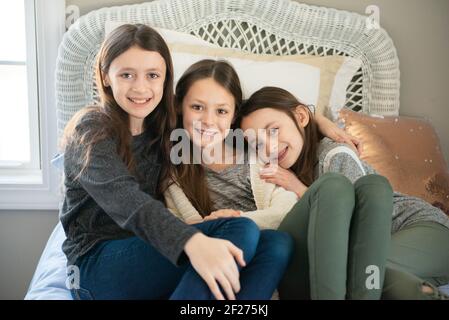 Tre sorelle felici che si coccolano insieme su un letto. Foto Stock