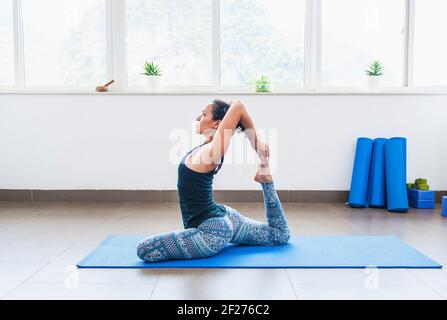 Donna di mezza età che pratica yoga nel suo appartamento a Yangshuo Foto Stock