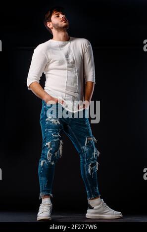 Ritratto di un giovane attraente vestito di jeans blu e pullover bianco Foto Stock