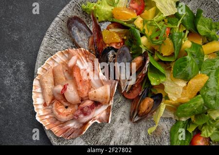 Insalata di pesce, tentacoli di polpo, capesante, gamberi di tigre, calamari, cozze, ananas, arancia, insalata mista, ciliegia, condimento arancione Foto Stock