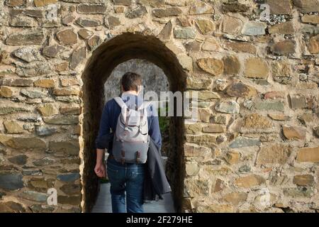 Uomo zaino in spalla turista viaggiatore a piedi nel castello muro di ingresso a Mertola Alentejo, Portogallo Foto Stock