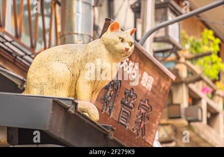 tokyo, giappone - febbraio 28 2021: Scultura raffigurante un gatto bianco che guarda verso il basso su un tetto nella via dello shopping Yanaka-Ginza conosciuta come luogo sacro per Foto Stock