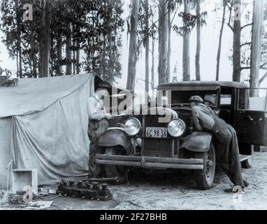 Pickers di piselli dal Vermont - 6 settimane guadagnano 7.00 dollari - al campo di squatter, Nipomo, CA. La fotografia mostra gli uomini che lavorano su un'automobile parcheggiata di fronte ad una tenda in un boschetto di eucalipto alberi.Febbraio 24, 1935 Fotografia di Dorotea Lange Foto Stock