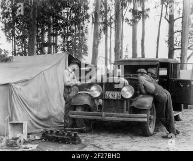 Pickers di piselli dal Vermont - 6 settimane guadagnano 7.00 dollari - al campo di squatter, Nipomo, CA. La fotografia mostra gli uomini che lavorano su un'automobile parcheggiata di fronte ad una tenda in un boschetto di eucalipto alberi.Febbraio 24, 1935 Fotografia di Dorotea Lange Foto Stock