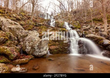 Immagine a lunga esposizione delle Dark Hallow Falls nel Parco Nazionale di Shenandoah in autunno. L'immagine presenta acqua a cascata che scende lungo la montagna coperta wi Foto Stock