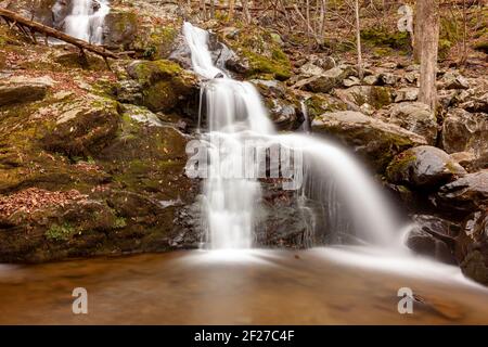 Immagine a lunga esposizione delle Dark Hallow Falls nel Parco Nazionale di Shenandoah in autunno. L'immagine presenta acqua a cascata che scende lungo la montagna coperta wi Foto Stock