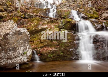 Immagine a lunga esposizione delle Dark Hallow Falls nel Parco Nazionale di Shenandoah in autunno. L'immagine presenta acqua a cascata che scende lungo la montagna coperta wi Foto Stock
