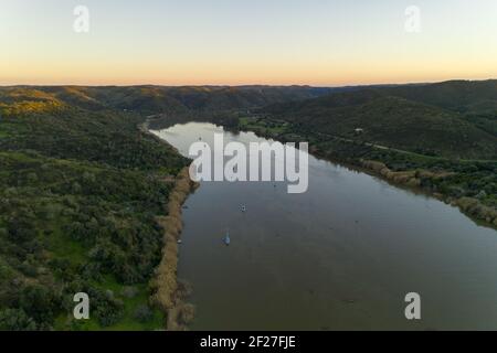Vista aerea del drone di Sanlucar de Guadiana in Spagna e Alcoutim in Portogallo con barche a vela sul fiume Guadiana Foto Stock