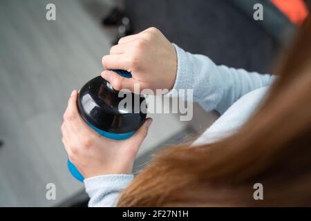 Primo piano sulle mani di donna caucasica sconosciuta che tiene il supplemento scuotere mentre ci si trova in camera all'apertura o alla chiusura di casa vista dall'alto Foto Stock
