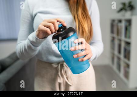 Primo piano sulle mani di donna caucasica sconosciuta che tiene il supplemento scuotere mentre ci si trova in camera all'apertura o alla chiusura di casa vista frontale Foto Stock